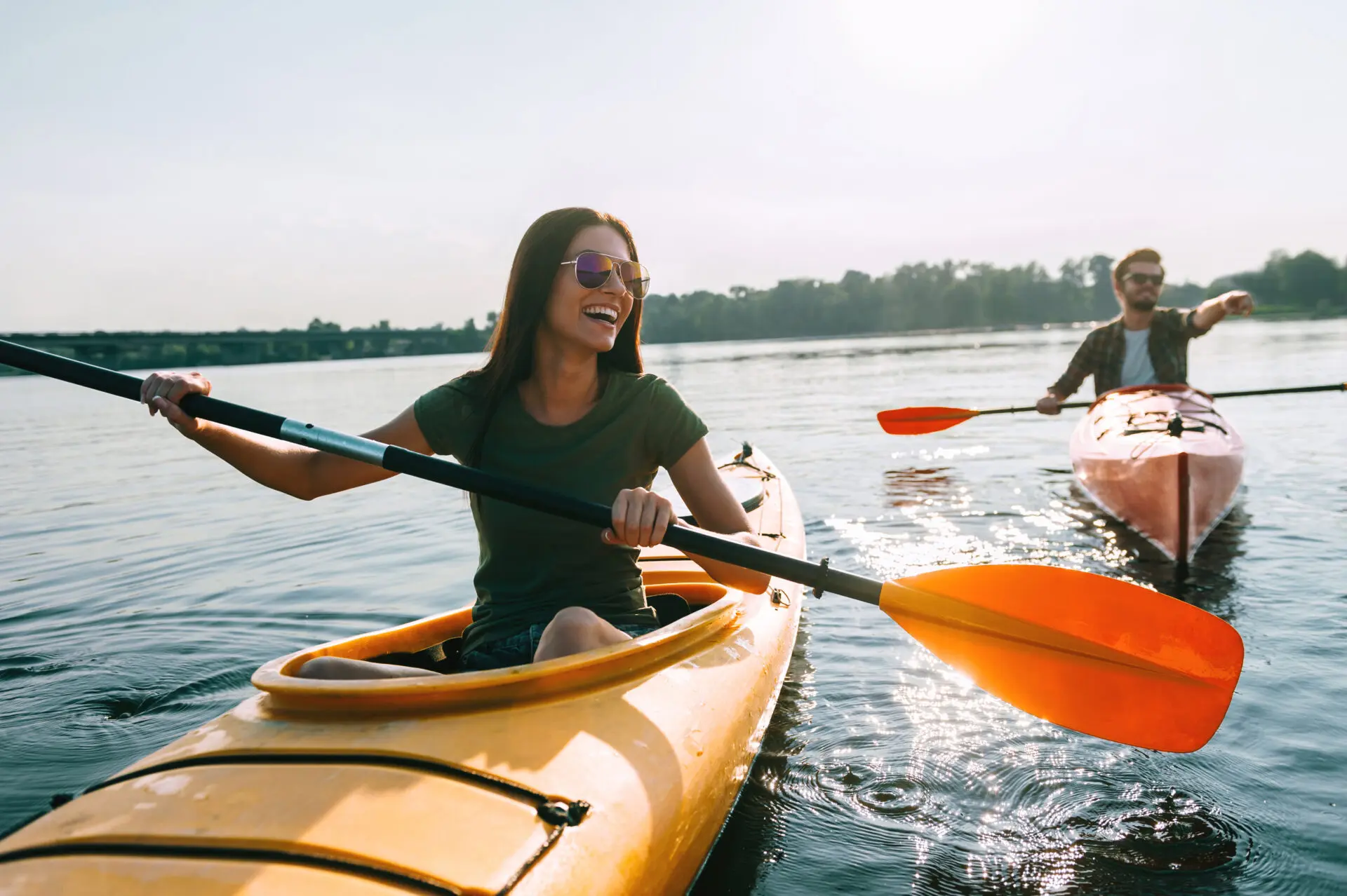 Beautiful young couple kayaking on lake together and smiling
